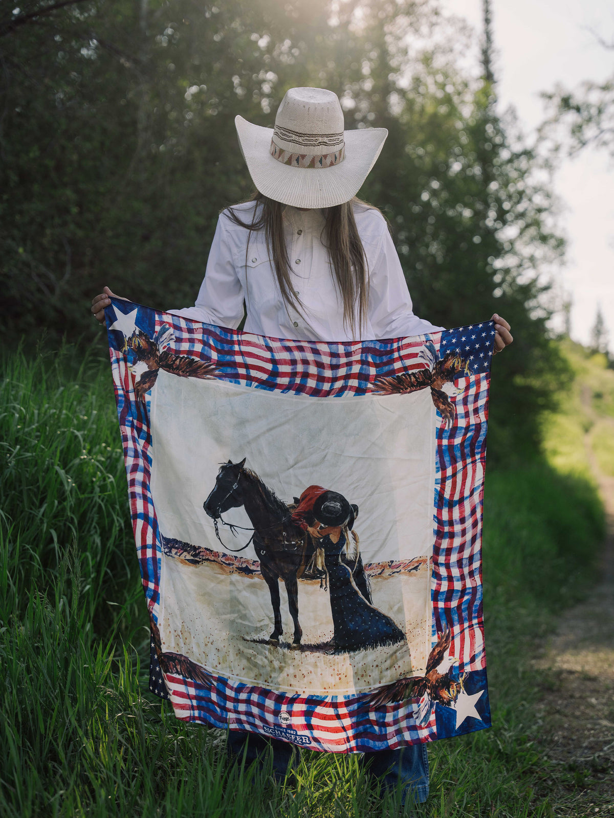 Red plaid and star wild rag scarf draped over hat, with horse artwork center.