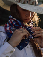 Wild rag neck scarf tied at collar with horse print; close-up on wearer.