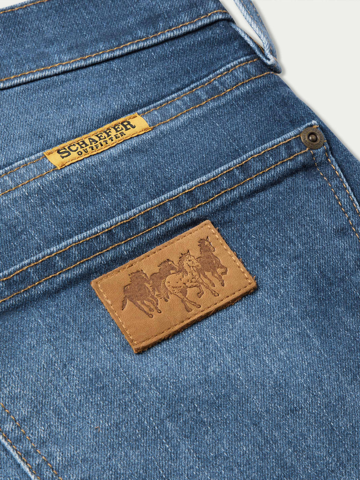 Denim dungarees back pocket with tan logo patch and double-row stitching