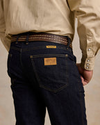 Dark rinse jeans back pocket close-up with leather patch and yoke stitching