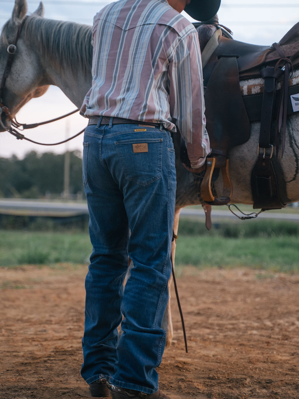 Medium-wash boot-cut dungaree jeans on model with rear pockets and belt loops