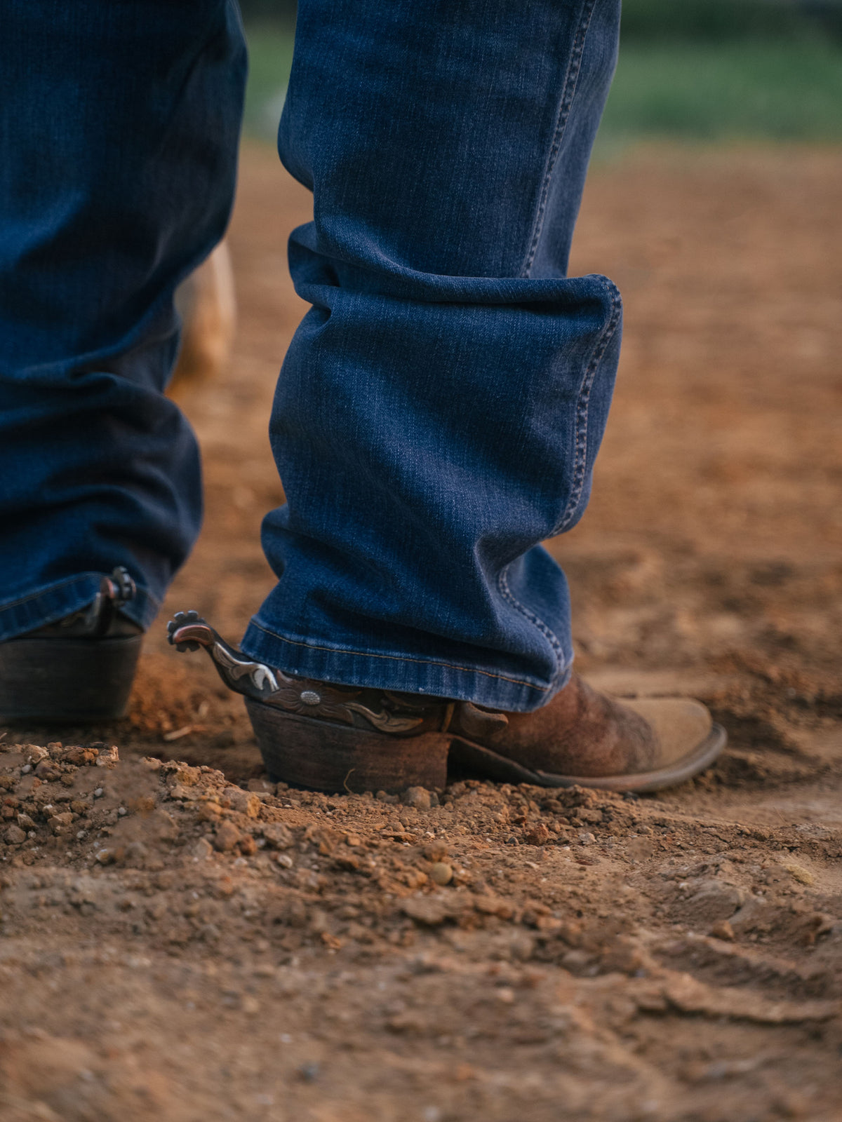 Medium-wash boot-cut dungaree jeans cuff with leather cowboy boots