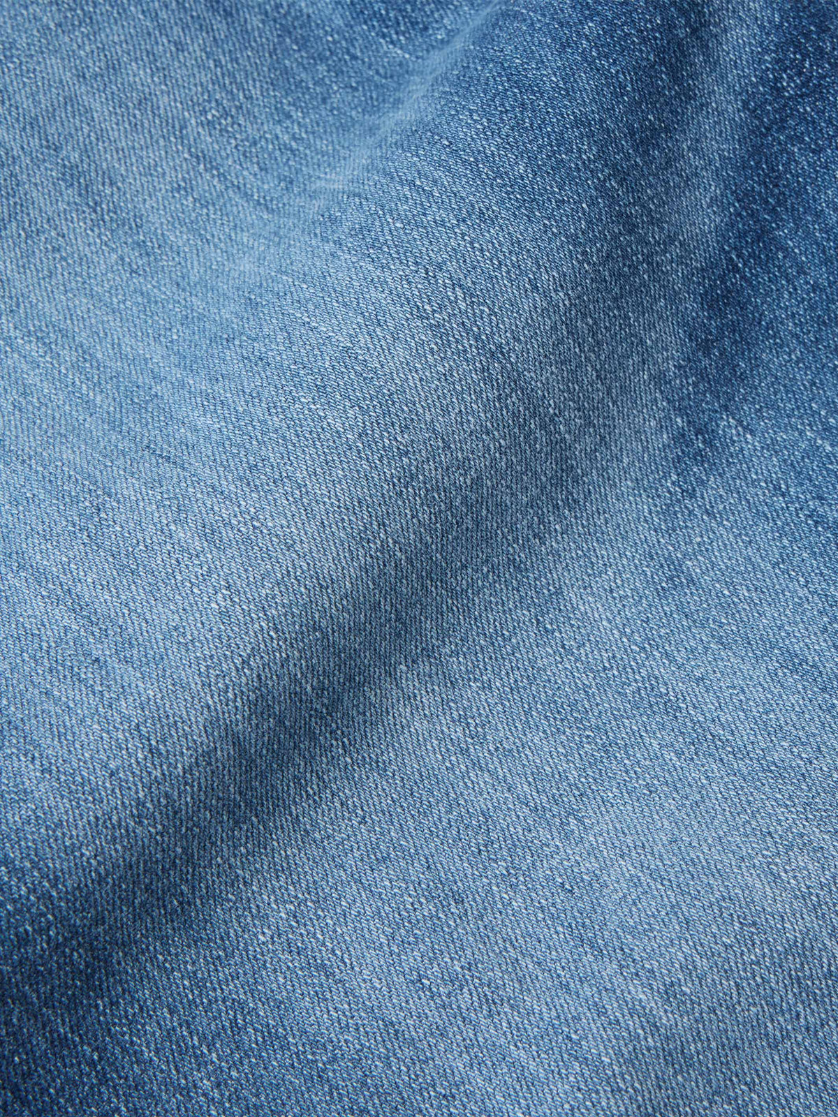 Medium-wash denim fabric texture close-up for boot-cut dungaree jeans