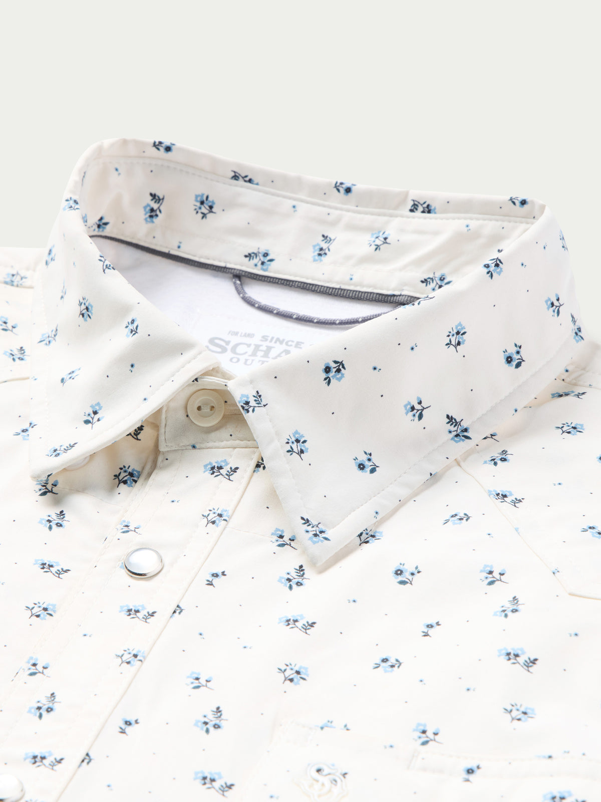 Short-sleeve pearl snap shirt collar and front placket, white with small blue floral print.