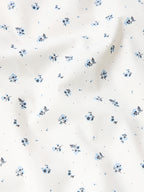 Close-up of white fabric with small blue floral dot pattern for short-sleeve pearl snap shirt.