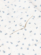 Short-sleeve pearl snap shirt detail: white fabric, blue floral print, round snap buttons.