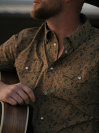 Western shirt neckline close-up with collar and pearl snap buttons on patterned fabric.