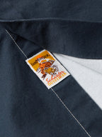 Button-down shirt fabric close-up with woven brand label on dark navy seam