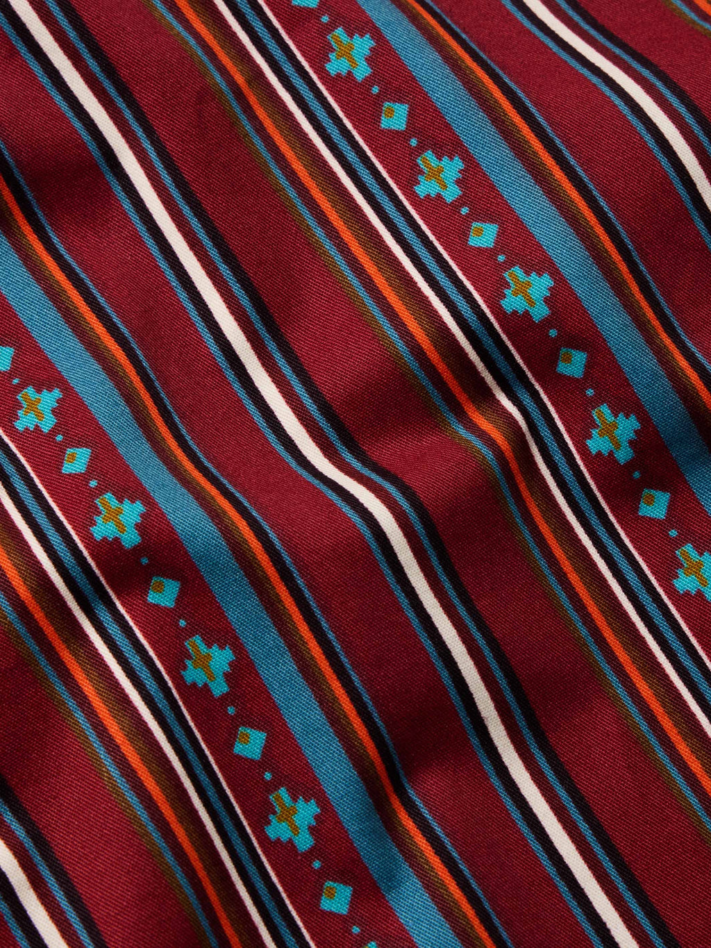 Close-up of red striped button-down with multicolor thin lines and teal geometric accents