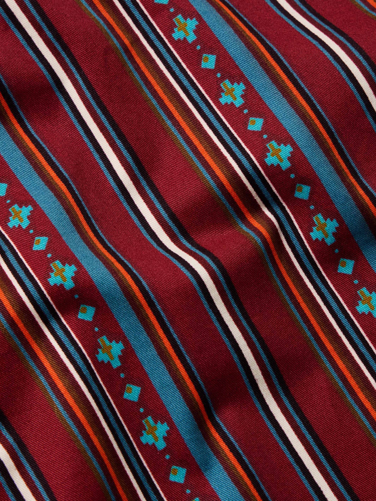 Close-up of red striped button-down with multicolor thin lines and teal geometric accents