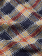 Multicolor flannel plaid fabric close-up with navy, orange, and cream grid lines.