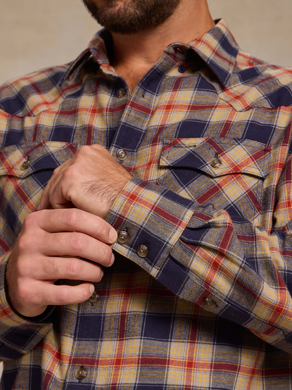 Plaid flannel button-down shirt close-up: cuff buttons and chest pocket flap.