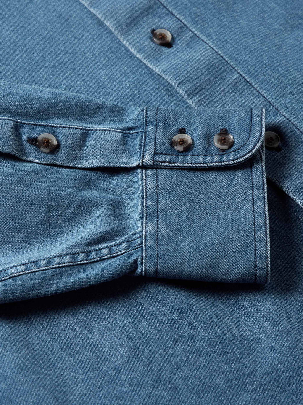 Light blue denim button-down shirt with two-button placket and chest pockets