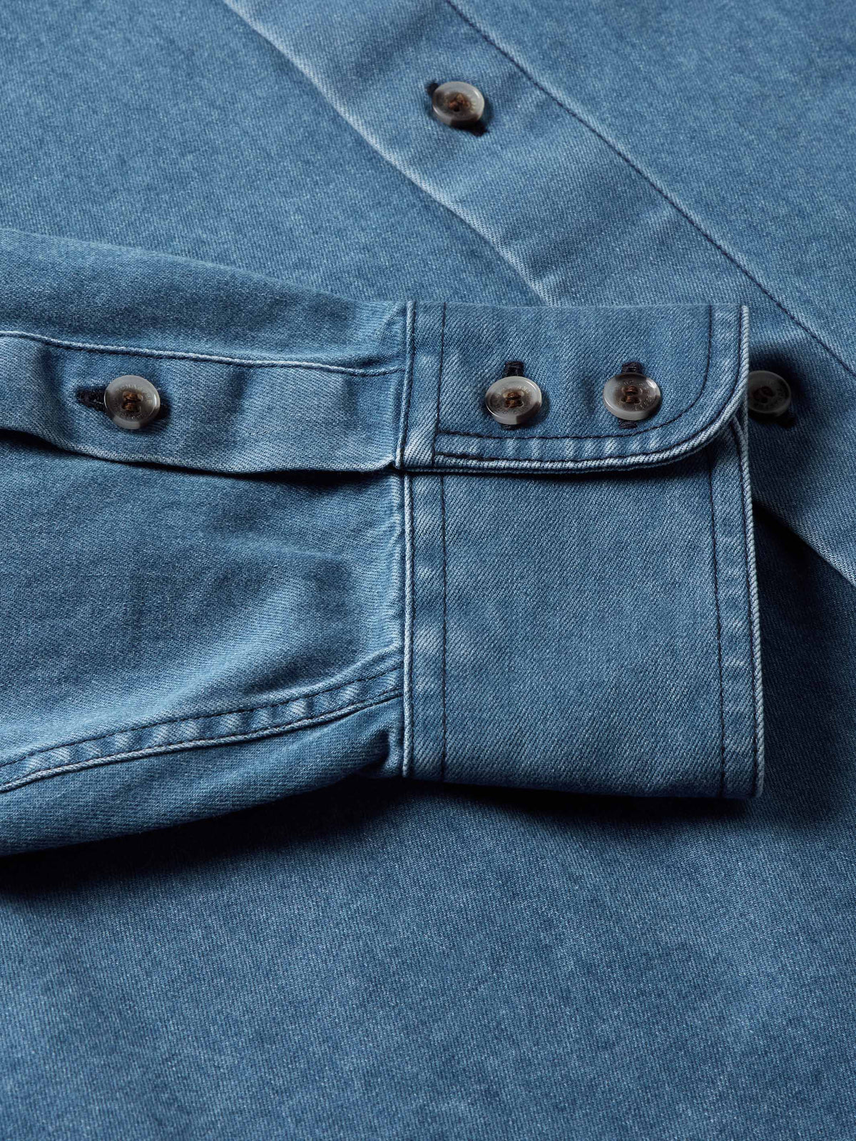 Light blue denim button-down shirt with two-button placket and chest pockets