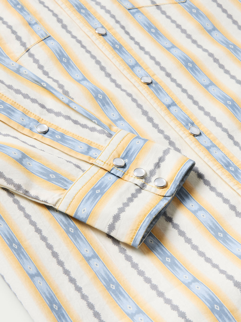 Cotton snap shirt front detail with light blue and white vertical stripes and white snap buttons
