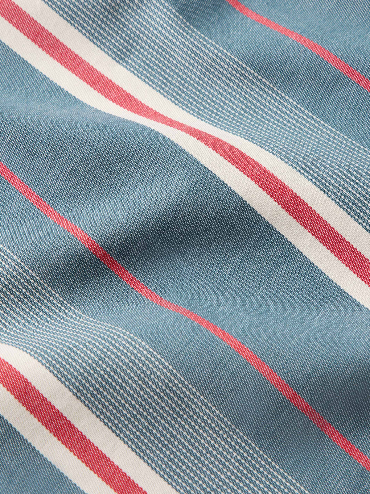 Light blue western snap shirt fabric close-up with red and white vertical stripes