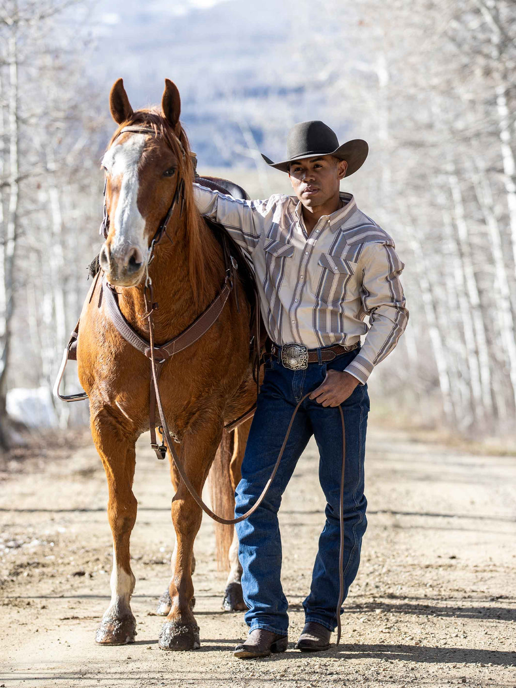 Western snap shirt in tan with blue and red stripes worn by a rider
