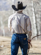 Western snap shirt in tan with blue and red stripes, back view worn outdoors