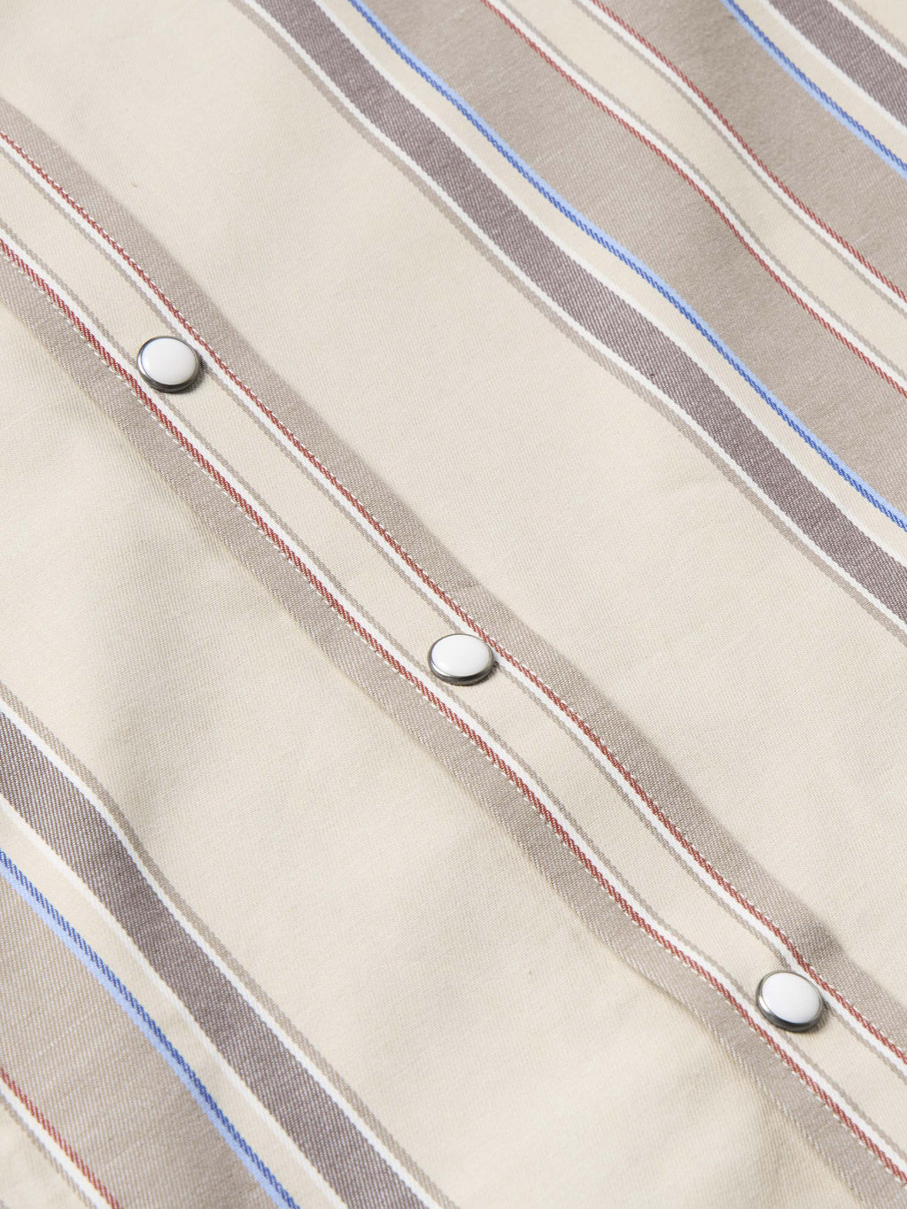 Western snap shirt in tan with blue and red vertical stripes, snap row detail