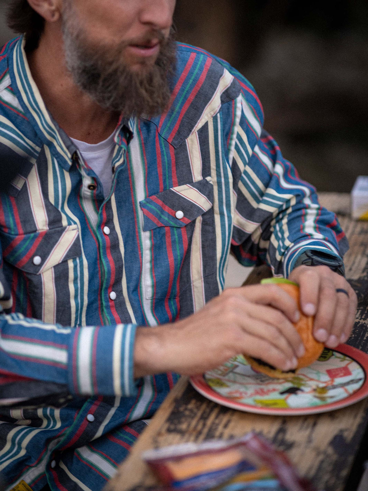 Man wearing Western snap shirt with multicolor stripe print, two chest pockets, snap buttons