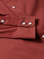 Oxblood snap cuff with metal buttons and stitched seams on the sleeve