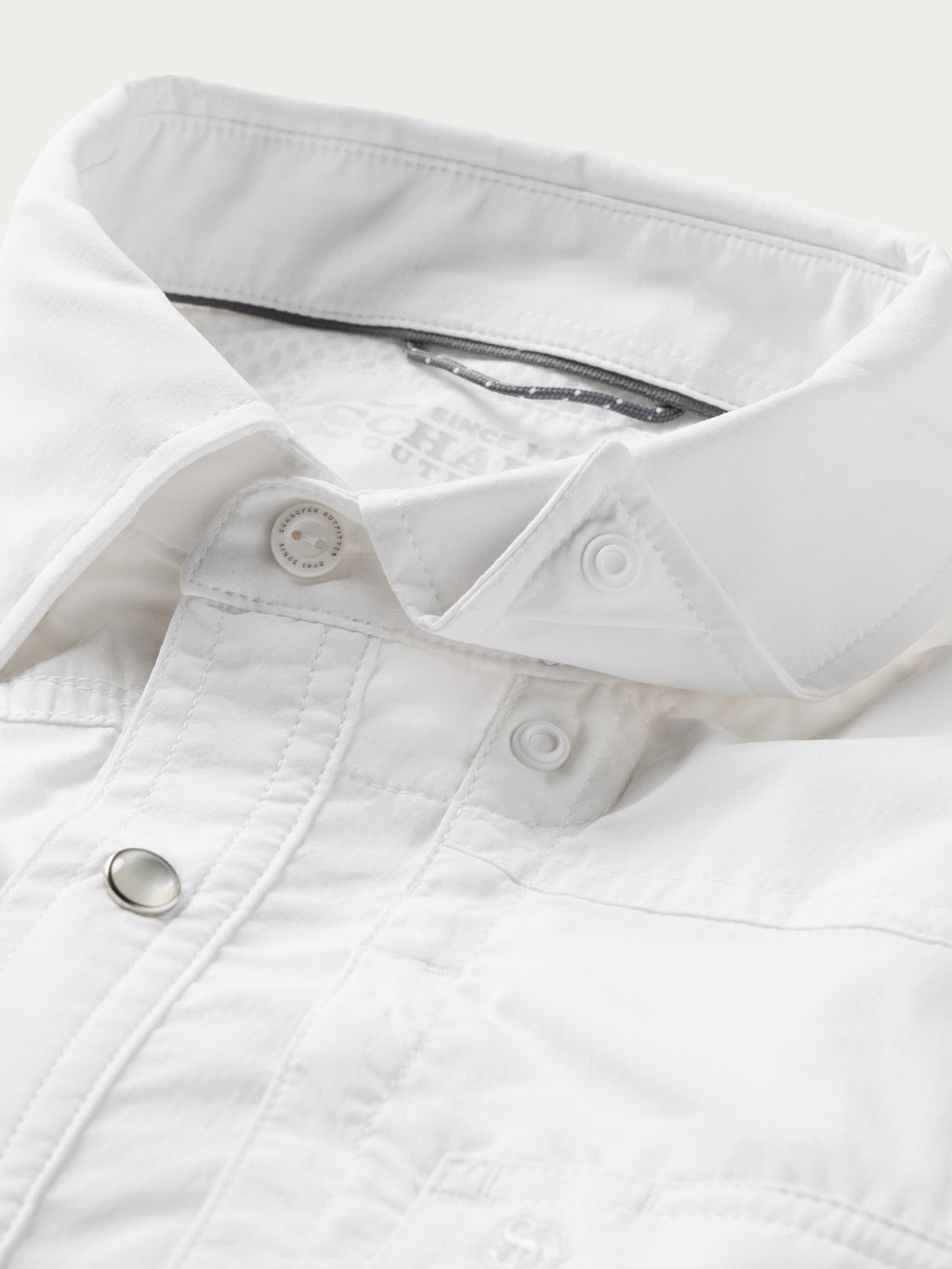 White snap shirt collar and placket detail with metal snap buttons close-up