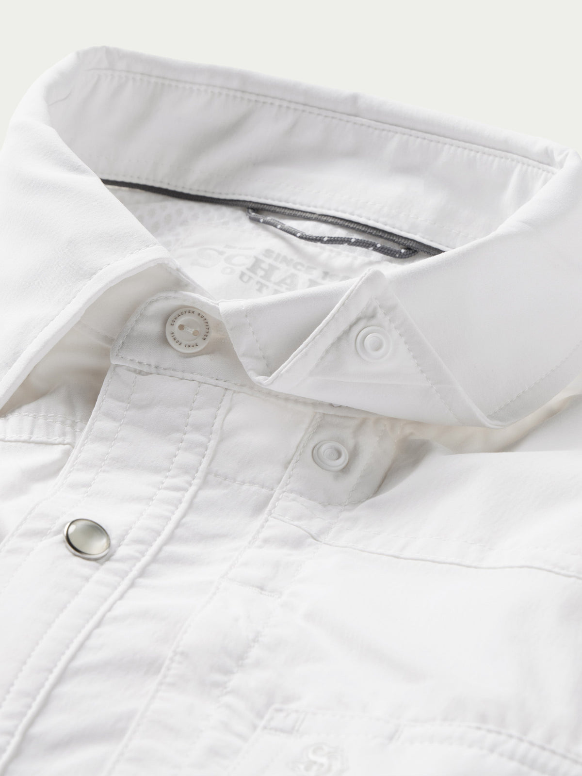 White snap shirt collar and placket detail with metal snap buttons close-up
