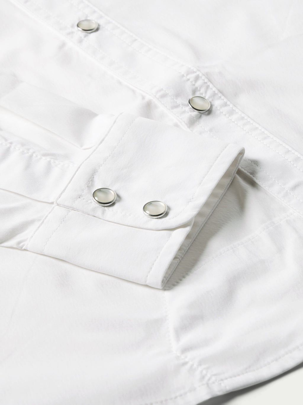 White western snap shirt cuffs with metal snap buttons and side seam detail close-up