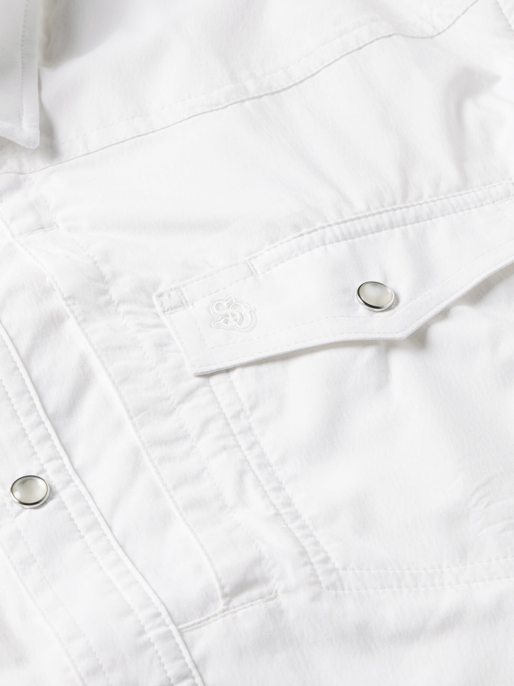 White snap shirt yoke seam with metal snap buttons and stitching close-up