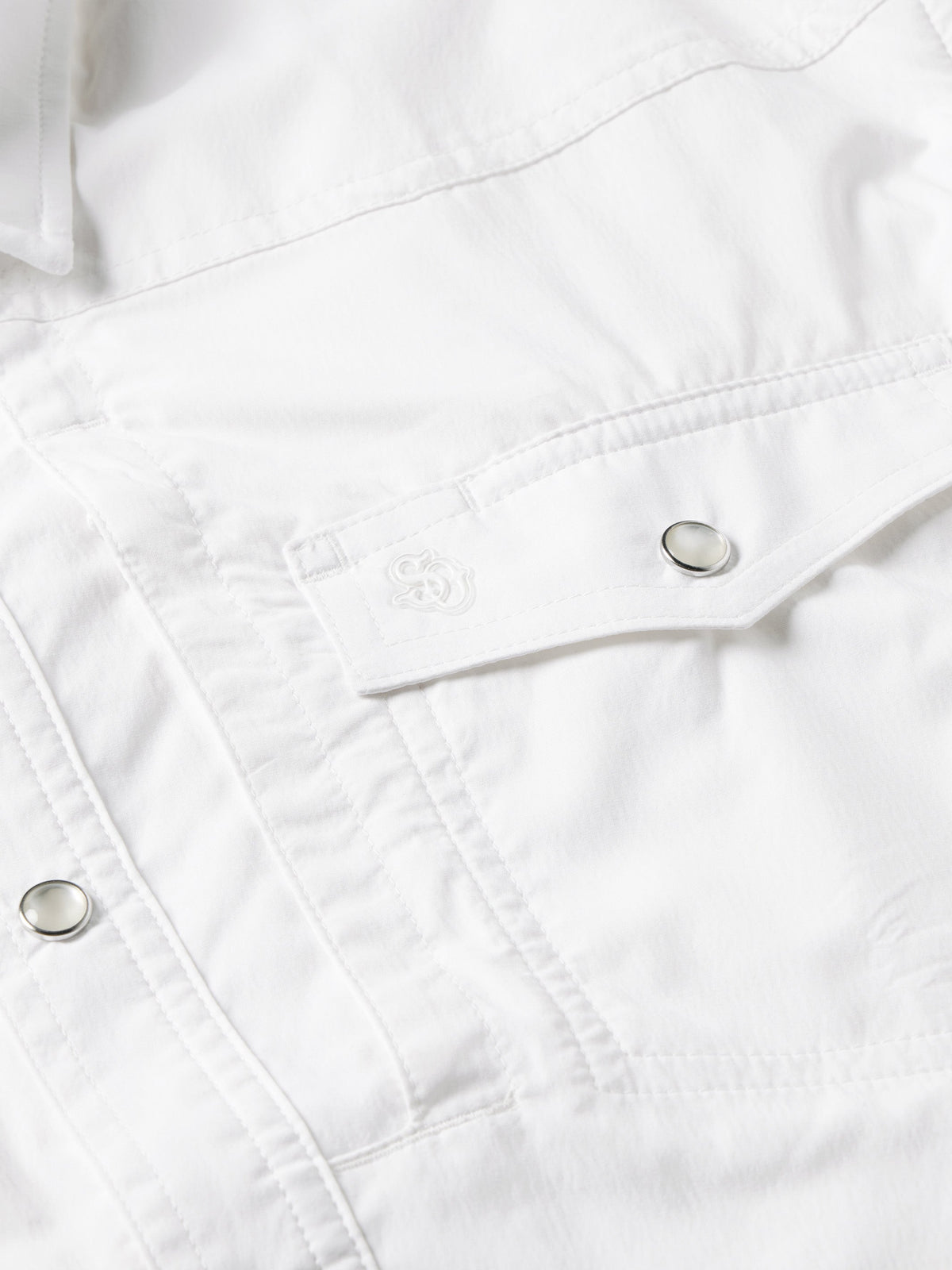 White snap shirt yoke seam with metal snap buttons and stitching close-up