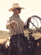 Men's pink striped button-up shirt on model with cowboy hat and saddle gear