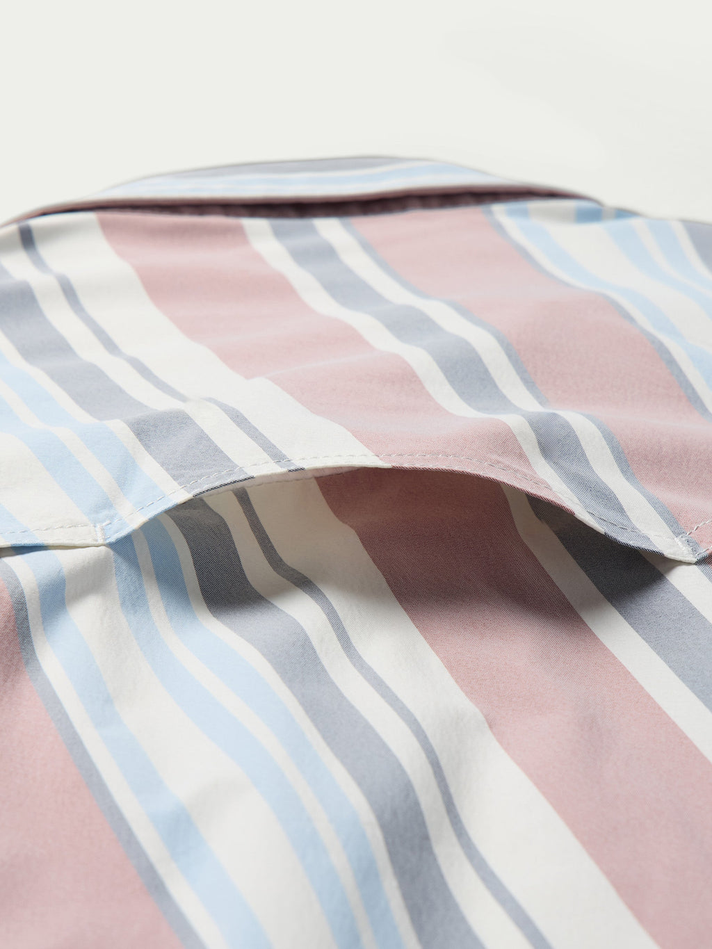 Close-up of men’s striped western snap shirt fabric with pink, blue, and white vertical stripes