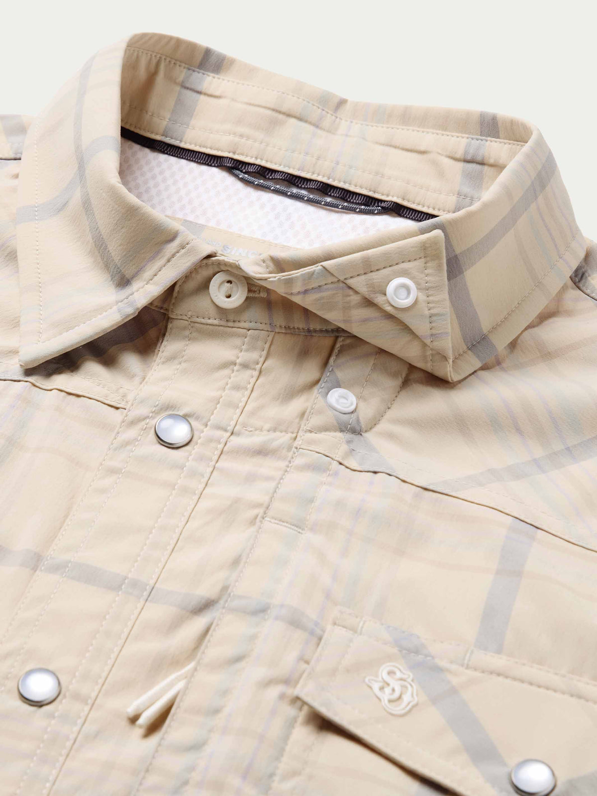Snap shirt collar detail, cream with blue plaid, snap front and chest pocket stitching.
