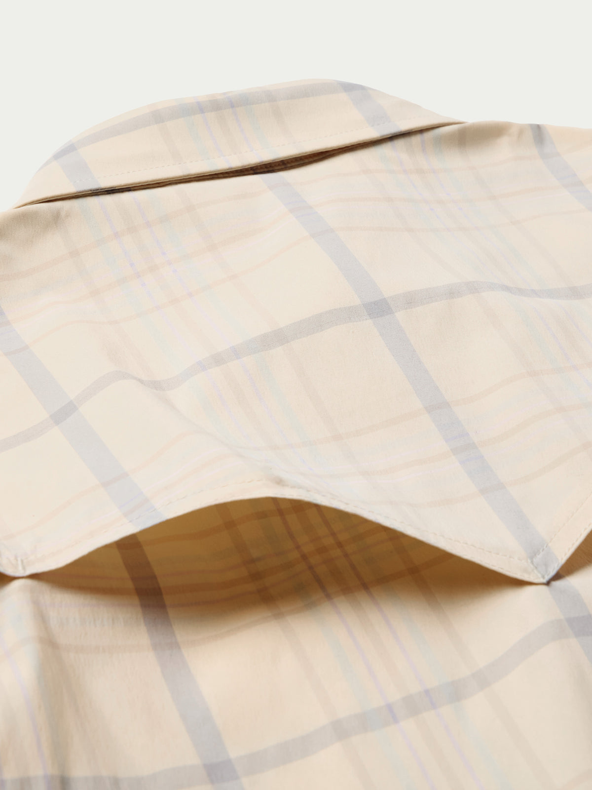 Tan plaid western snap shirt with curved yoke and snap-front placket