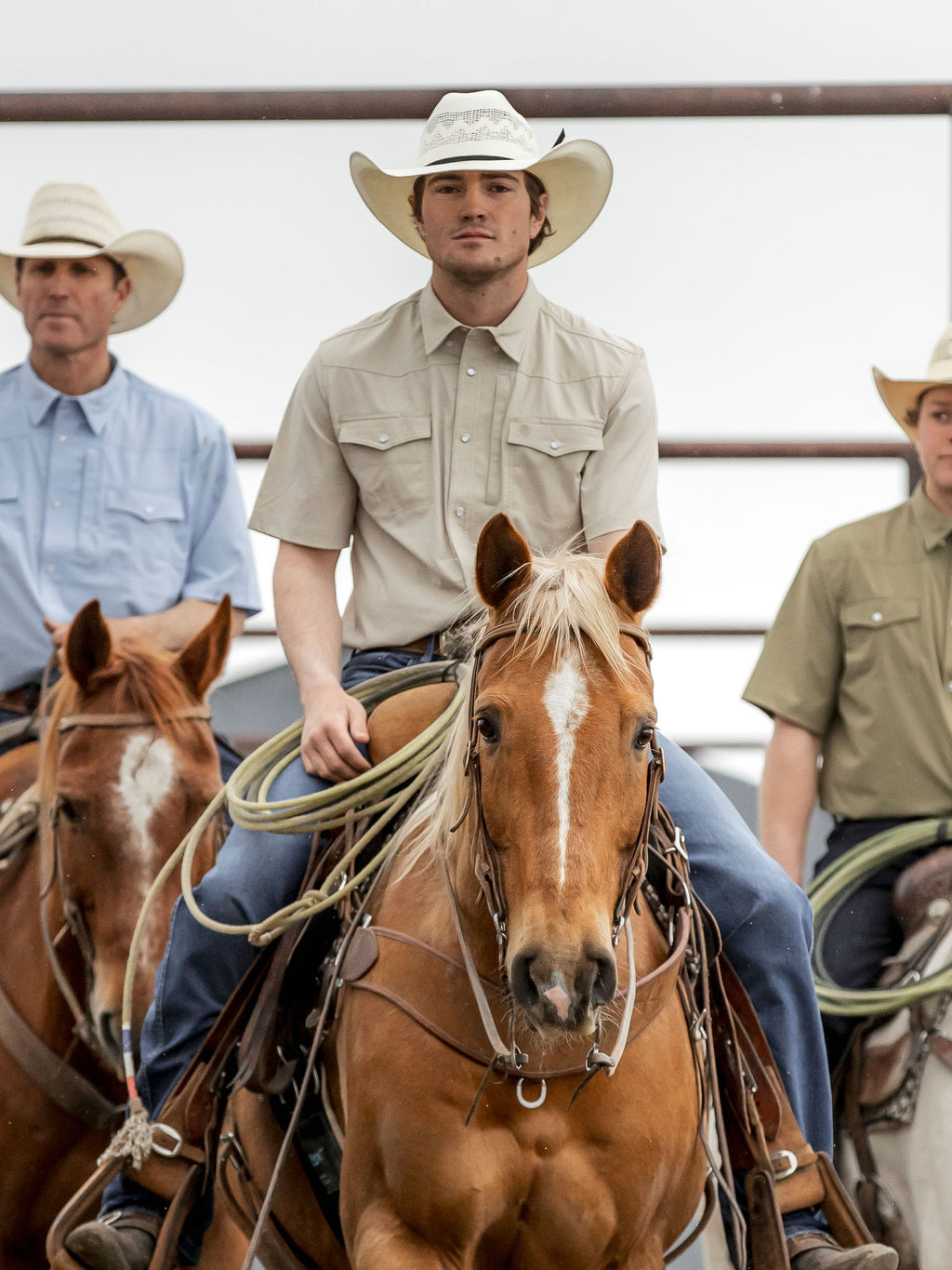 Khaki short-sleeve Western snap shirt worn by cowboy near horses