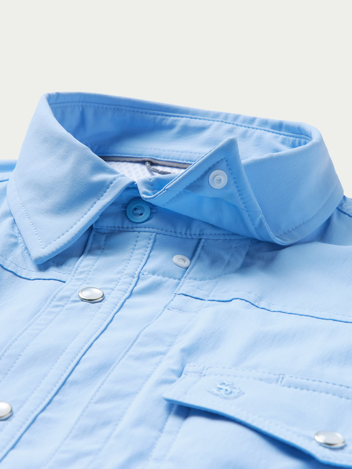 Close-up of sky blue shirt collar and snap placket with buttoned tab