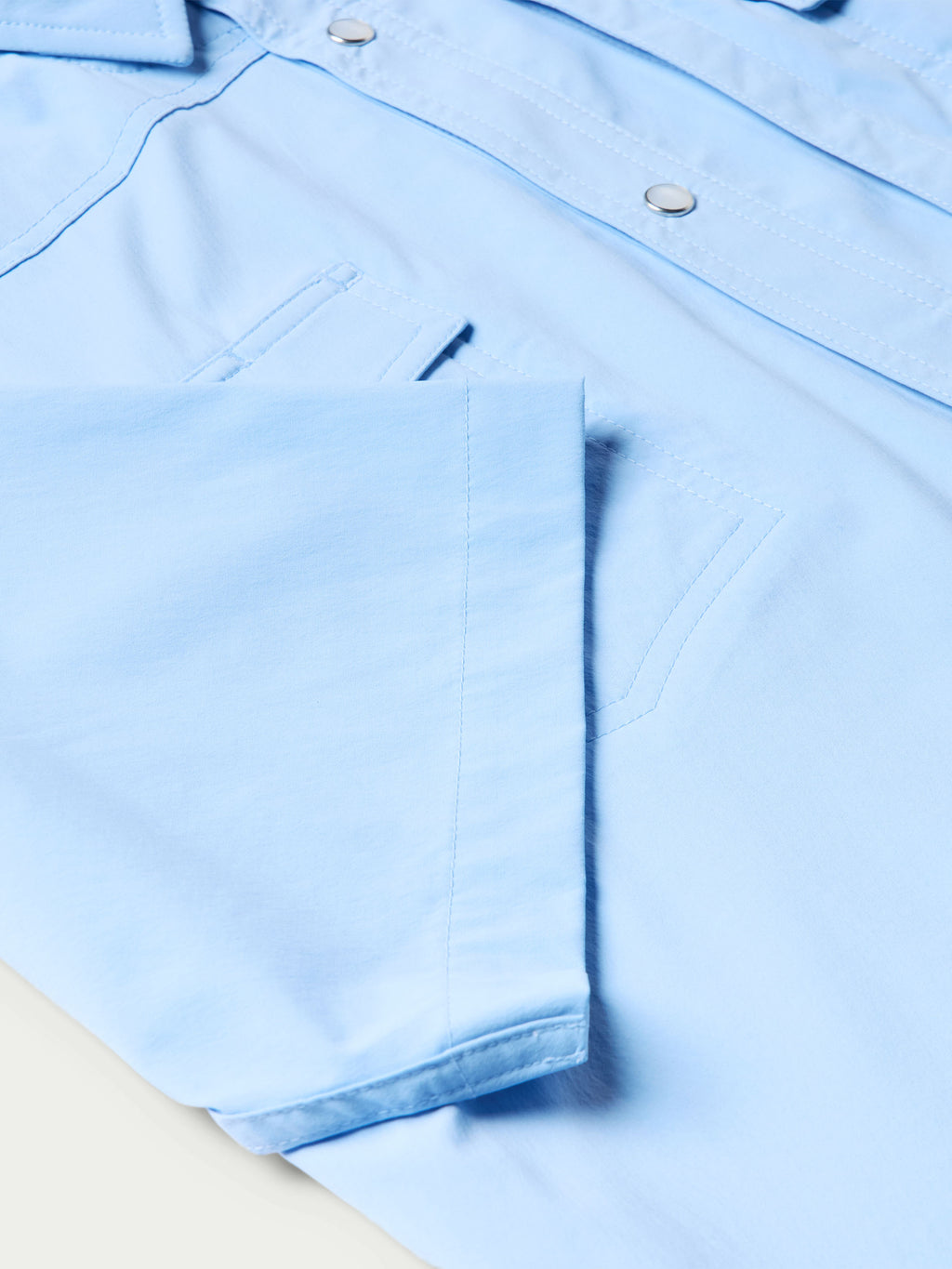 Close-up of sky blue shirt with short sleeves and snap tabs on shoulder