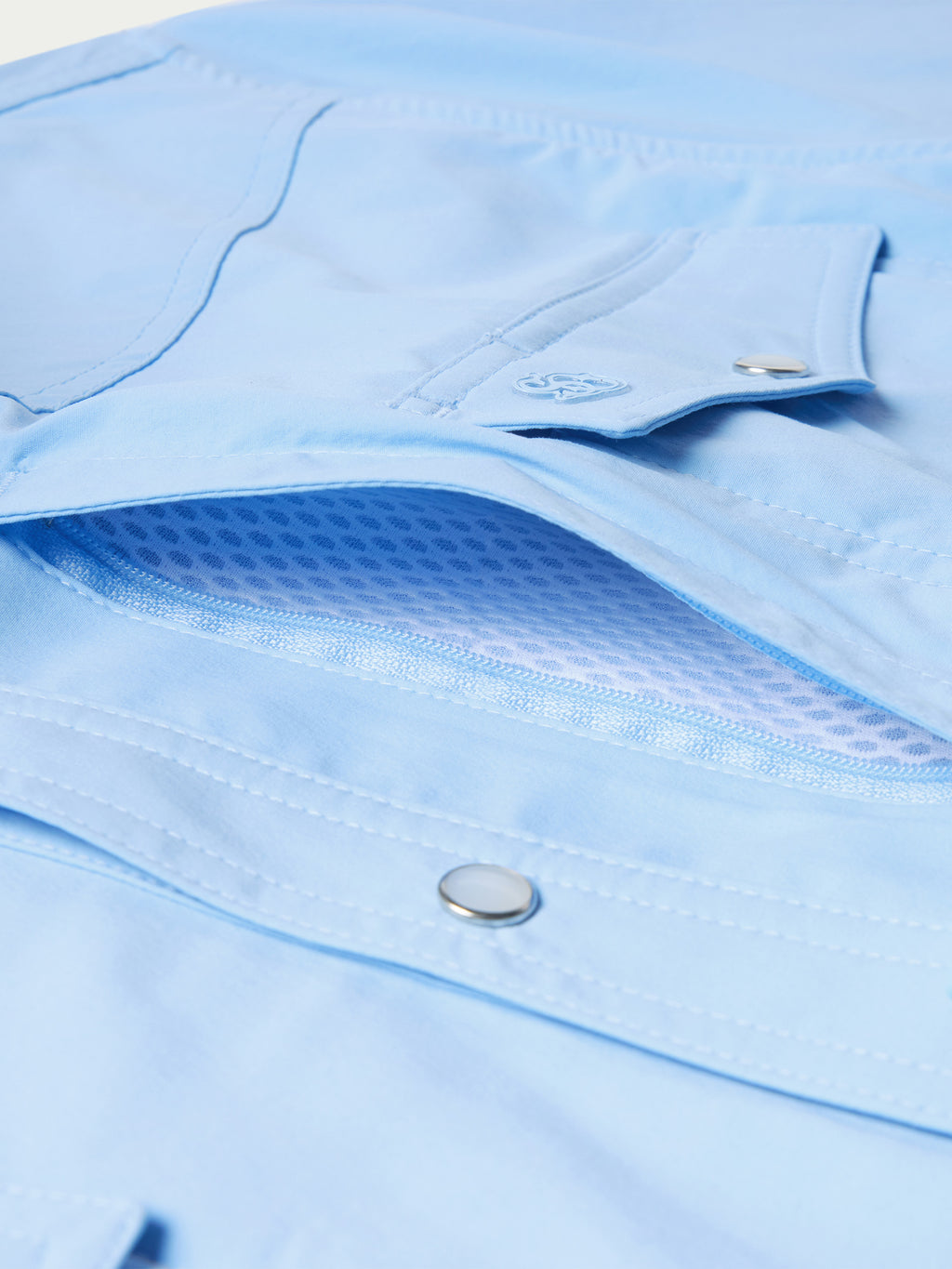 Close-up of sky blue fabric texture and snap on lower pocket flap