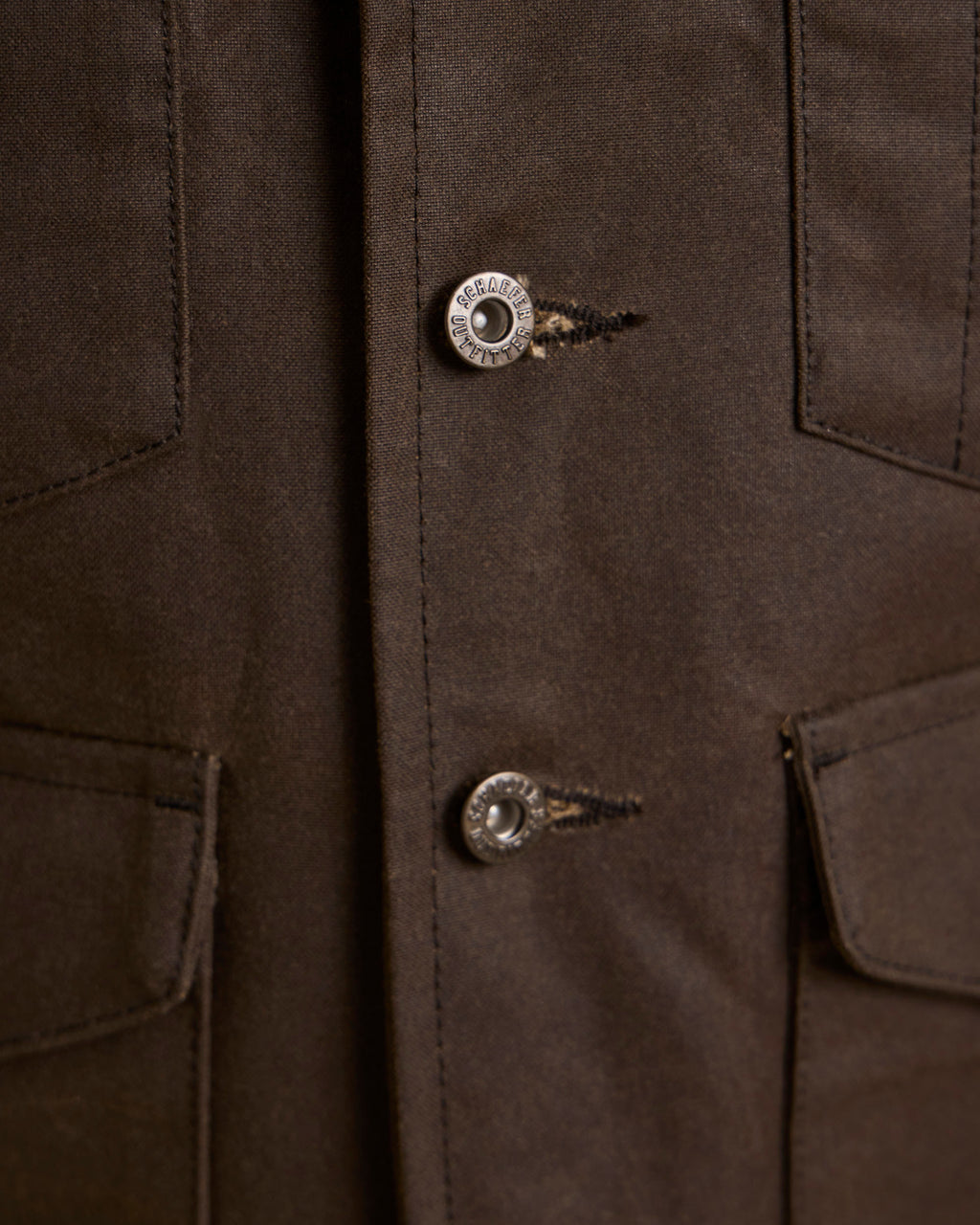 Close-up of dark brown vest with metal snap buttons and stitched placket