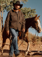 Dark brown quilted jacket worn by rider, corduroy collar and snap pockets visible