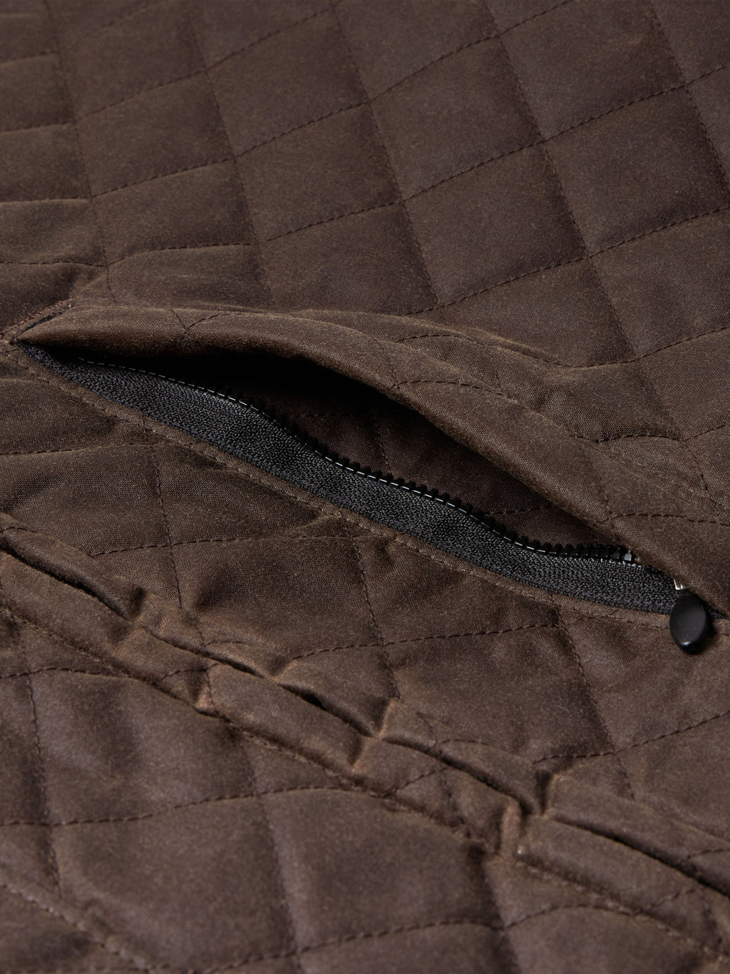 Dark brown quilted jacket with black zipper detail at side opening