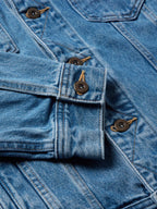 Medium indigo denim jacket front close-up of flap pockets and snap buttons