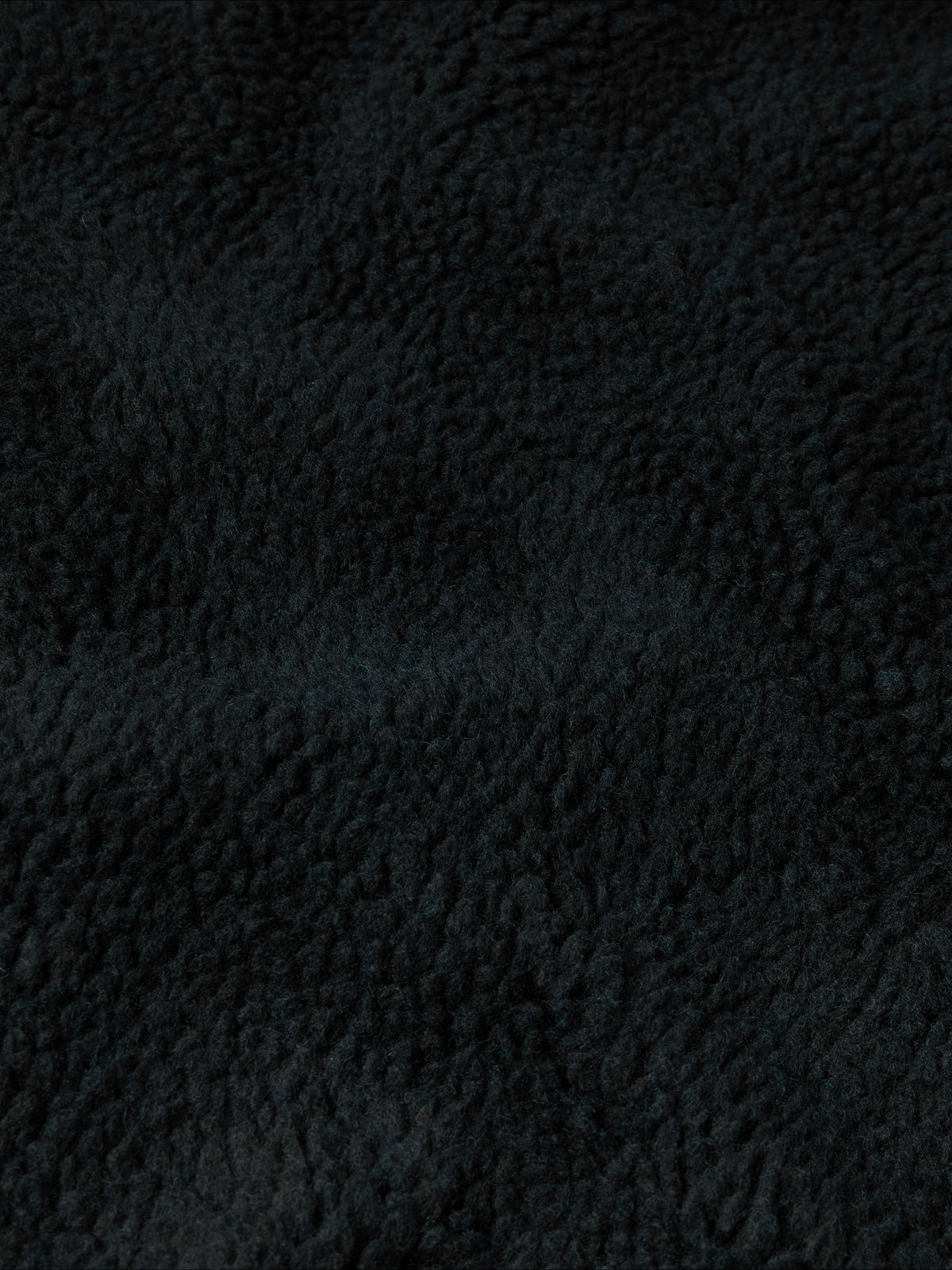 Black fleece fabric close-up with dense textured pile.