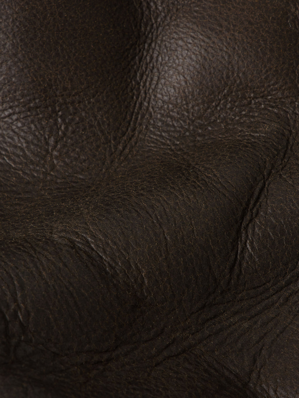 Close-up of dark brown pebbled leather texture and stitching