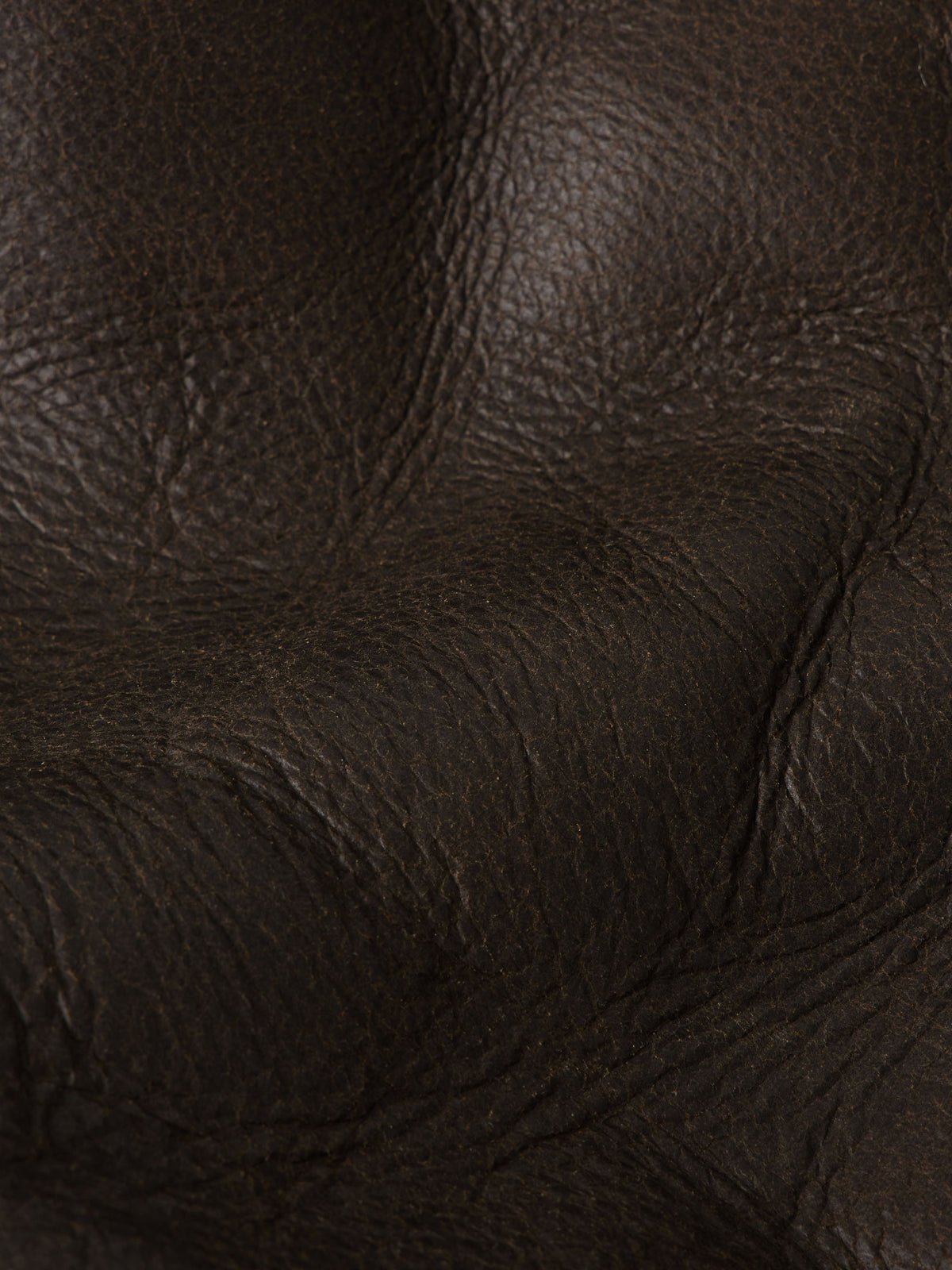Close-up of dark brown pebbled leather texture and stitching