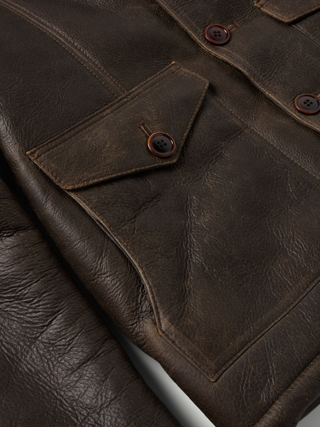 Leather coat front pocket and button detail with visible stitching