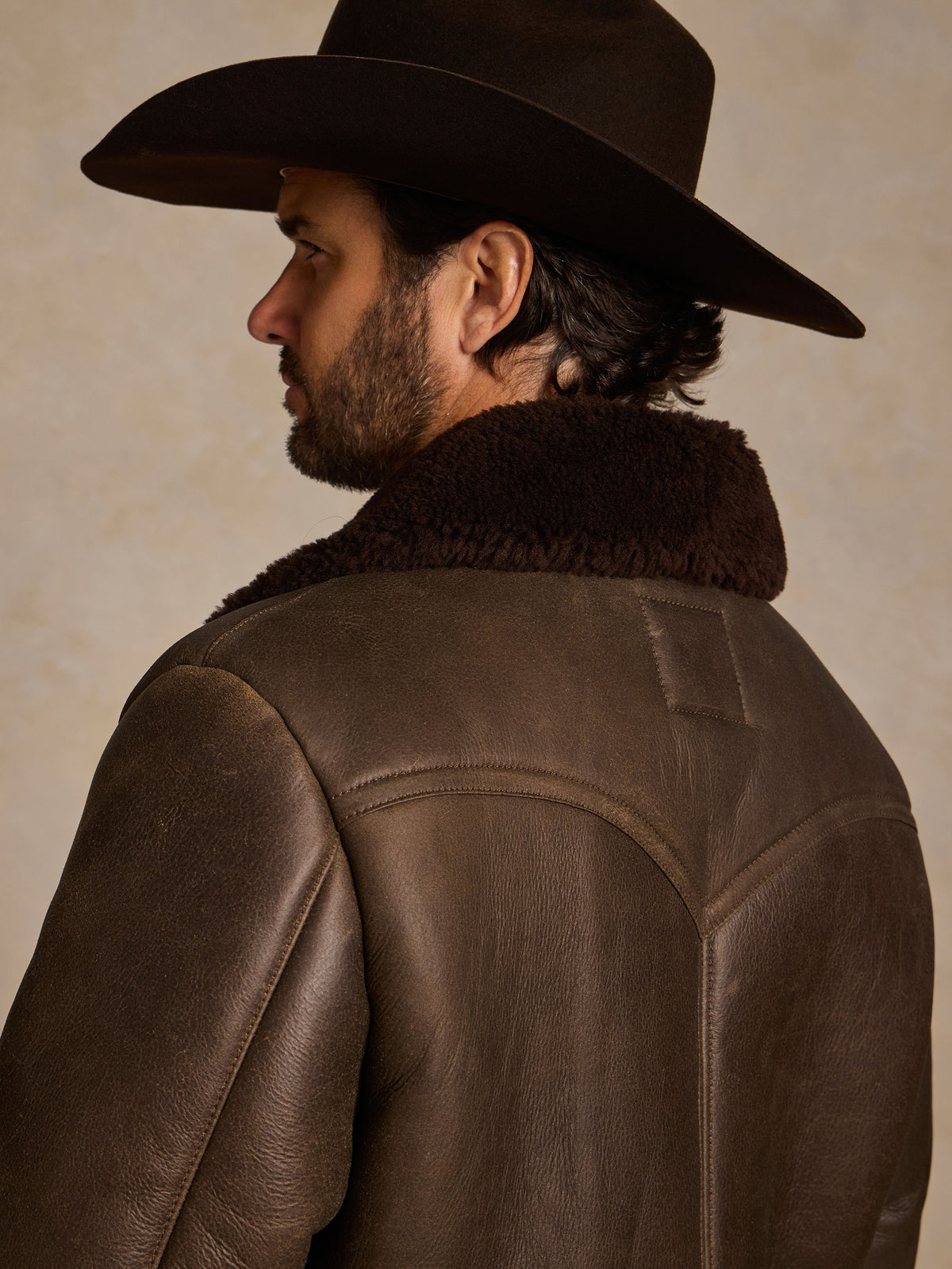 Men's dark brown shearling coat with thick fur collar, side view