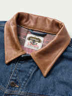 Tan leather collar with woven label on blue denim jacket
