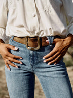 Medium wash denim jeans with belt loops, brown belt, and front button closure