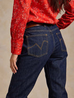 Dark denim jeans on model with western-style stitched pockets and straight fit